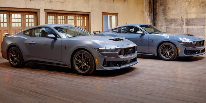 Two 2026 Ford Mustang performance coupes in a gray exterior finish, showcasing aggressive front styling, aerodynamic design, and sporty stance.